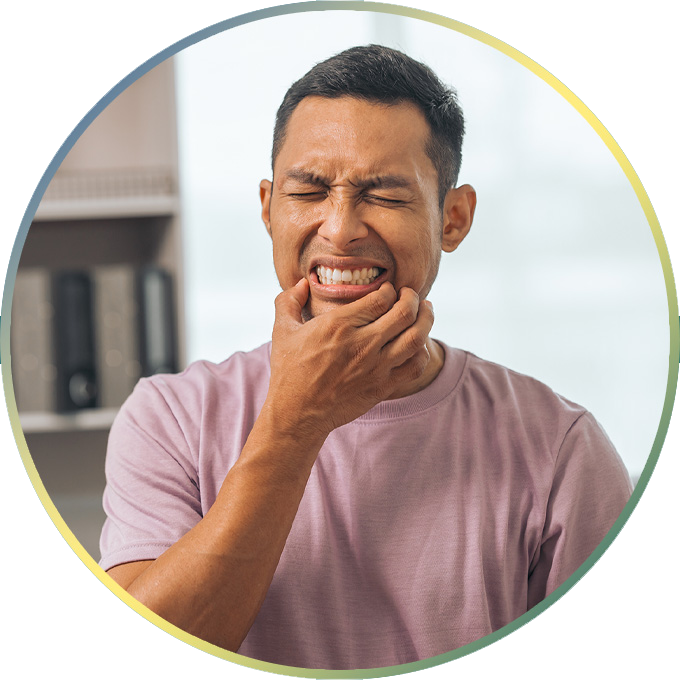 Man wincing in pain as he holds his mouth