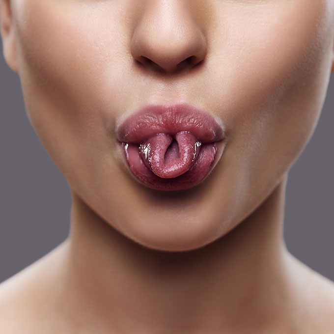 Close-up of a woman curling her tongue to illustrate the focus of Orofacial Myofunctional Therapy.